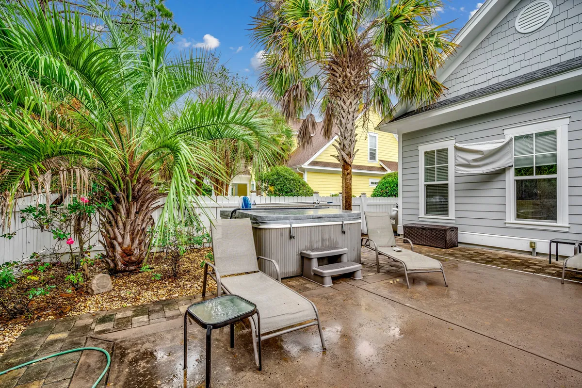 A serene hot tub sits at the edge of the pool area, framed by palm trees and lounge chairs. The space is designed for both sunbathing and tranquil hot tub soaks, with plenty of privacy and sunset views promised by the lush landscaping.