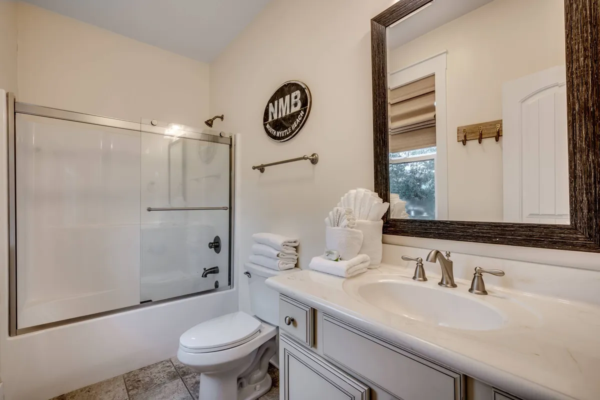 A spacious bathroom featuring a vanity with double sinks, a large mirror, and a glass shower. Plush towels and soothing lighting enhance the spa-like ambiance, making it ideal for morning routines or unwinding after a day out.