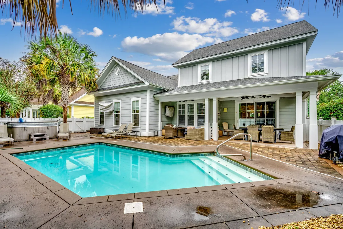 A spacious outdoor area featuring a sparkling swimming pool surrounded by palm trees, inviting lounge chairs, and an outdoor seating area ideal for relaxing or gathering. The warm lighting and lush greenery create a welcoming, family-friendly atmosphere perfect for enjoying the private heated pool experience described in the section.