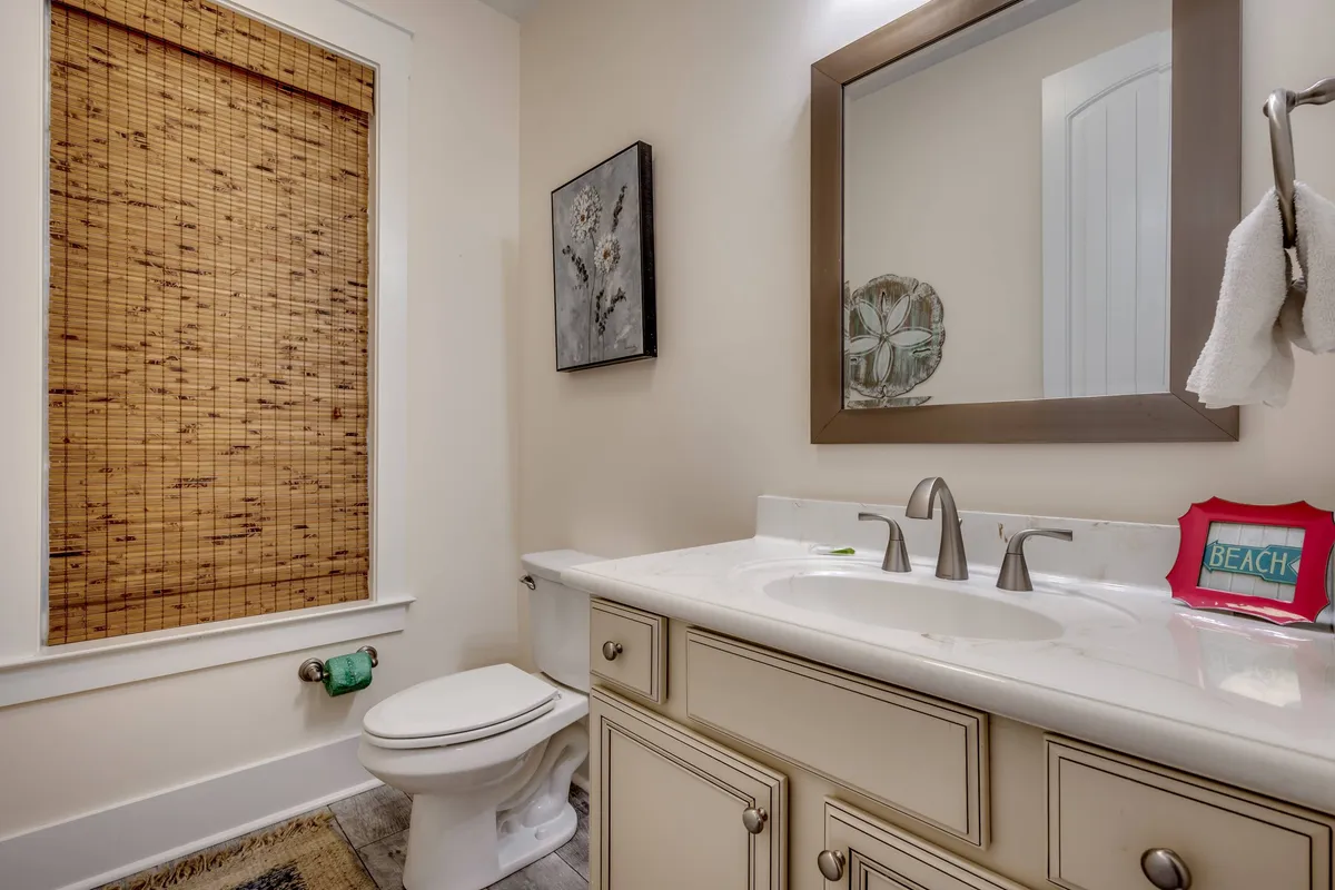 A calm, inviting interior bathroom space featuring a vanity with sink, a framed mirror, and beach-themed décor. The soft lighting and soothing decor evoke a spa-like ambiance ideal for self-care and relaxation.