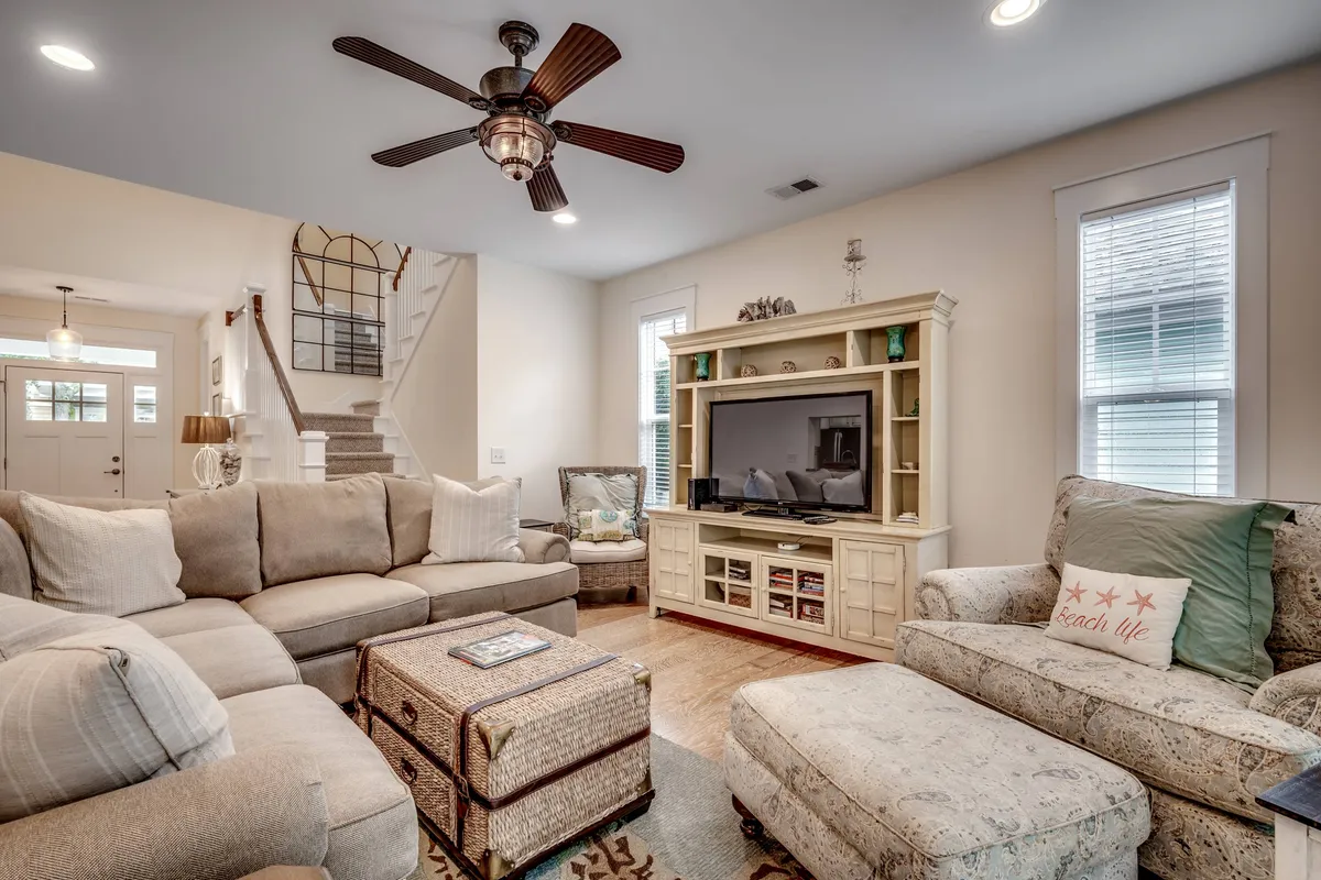 A cozy living room with a large sectional sofa, coffee table, and a television unit. Decorative pillows and warm lighting set a welcoming, inviting mood ideal for family movie nights, board games, and relaxed gatherings.