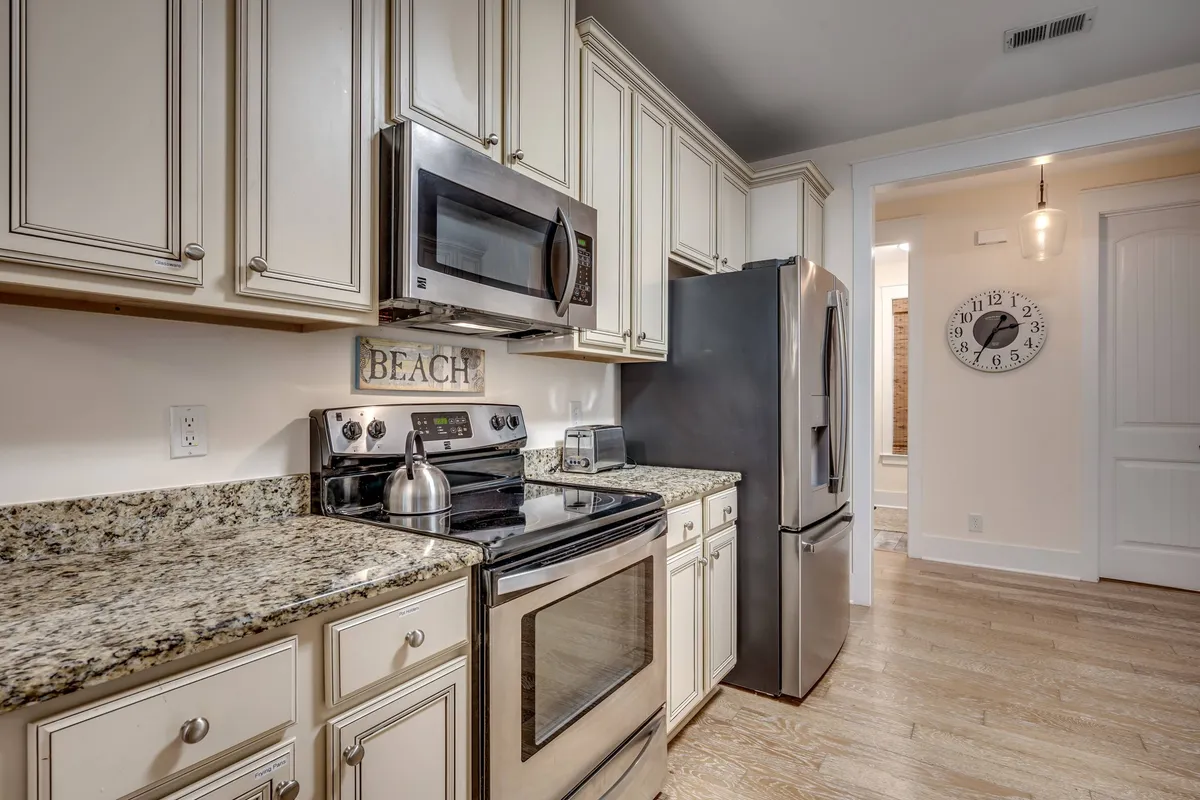 A spacious kitchen with gleaming granite countertops and stainless steel appliances, set against a backdrop of beach-themed decor. The setting exudes a casual and relaxed vibe, perfect for cooking, entertaining, and enjoying family gatherings.