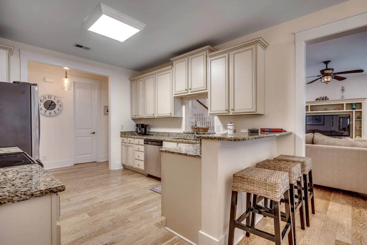 A bright, open kitchen featuring a granite countertop with bar stools that seamlessly connects to the living area. The space is designed for casual dining, entertaining, and easy flow between cooking and socializing.